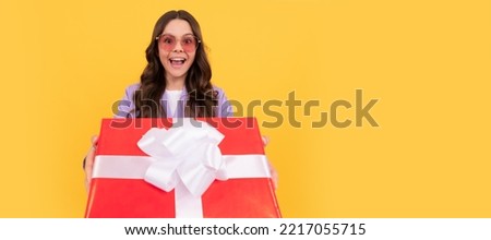 trendy surprised teen girl in sunglasses and suit share present box on yellow background, selective focus, purchase. Teenager girl with birthday gift, horizontal poster. Banner header with copy space.