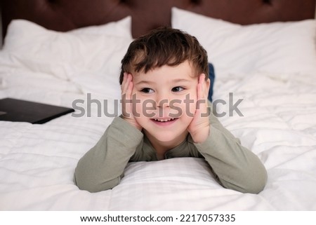 expressive young boy watching tv on the bed in the hotel room