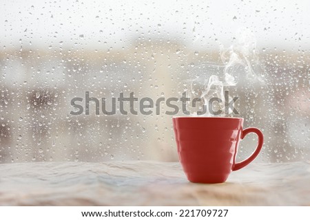 Steaming coffee cup on a rainy day window background  Royalty-Free Stock Photo #221709727