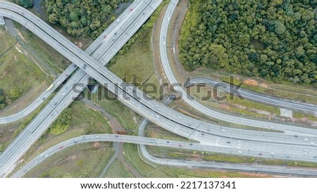 Aerial view directly above a six lane highway. Top view of asphalt road passes through the field and forest. Aerial. Sedan cars driving by the highway. Top view from drone. aerial photo autobahn road Royalty-Free Stock Photo #2217137341