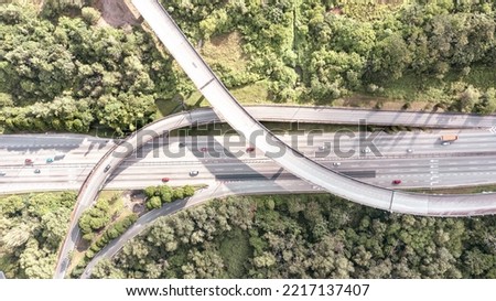 Aerial view directly above a six lane highway. Top view of asphalt road passes through the field and forest. Aerial. Sedan cars driving by the highway. Top view from drone. aerial photo autobahn road Royalty-Free Stock Photo #2217137407