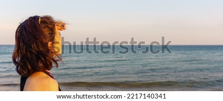 Woman looking at distant empty blue sky and sea. High resolution photo image can be used as large printed canvas, website banner, social media post. Blank copy space for advertising texts.
