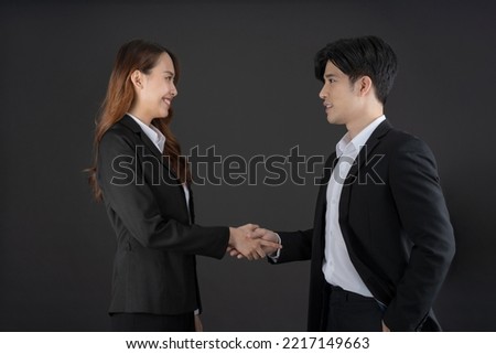 The two young businessmen shook hands to congratulate the successful business together.