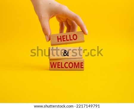 Hello and Welcome symbol. Concept words Hello and Welcome on wooden blocks. Beautiful yellow background. Businessman hand. Business and Hello and Welcome concept. Copy space.