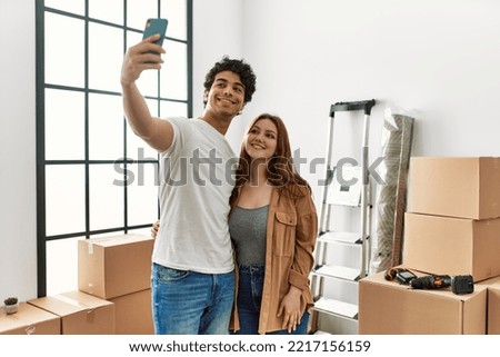 Young couple smiling happy making selfie by the smartphone at new home.