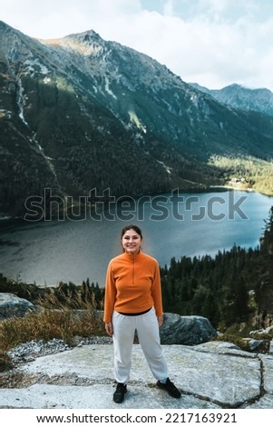 Sporty woman on the top of the mountain. Casual hiking in the mountains. Beautiful sky, lakes, forests and mountain peaks