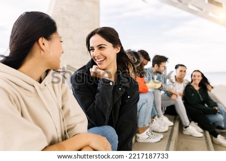 Happy young group of multiracial friends hanging out together outdoors - Millennial diverse people social gathering relaxing in city street - Focus on pretty caucasian woman Royalty-Free Stock Photo #2217187733