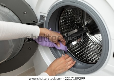 The concept of cleaning the details of a washing white machine, a stainless steel drum inside, close-up, no face Royalty-Free Stock Photo #2217189299