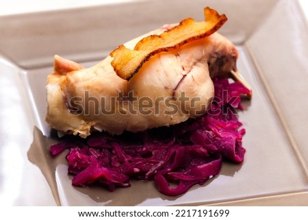 rabbit leg baked with bacon and served with red cabbage