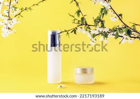 cosmetic containers and a sprig of plum blossoms on a yellow background, selective focus