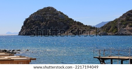 photo of clear, turquoise azure color sea and sky, photo of big rocks and far away islands, smooth and wavy sea, reflected sunshine