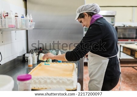 Female confectioner decorating large cake