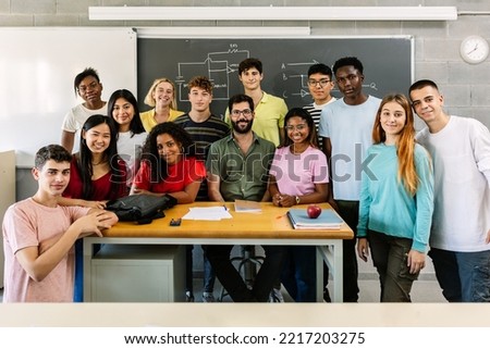 Large group portrait of millennial diverse students with male teacher smiling at camera standing together in classroom - High school teenage people posing for a group photo - Education concept Royalty-Free Stock Photo #2217203275
