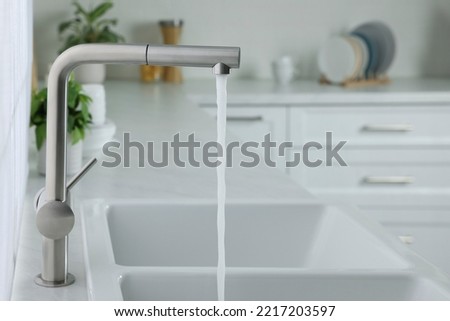 Stream of water flowing from tap in kitchen, space for text Royalty-Free Stock Photo #2217203597