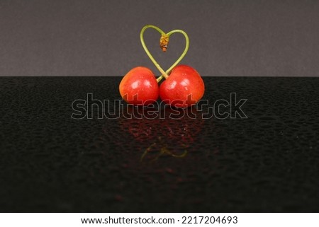 Two heart-shaped cherries on a black acrylic background. High resolution photo. Full depth of field.
