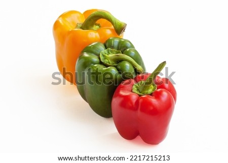 Peppers of different colors aligned in perspective on a white background
