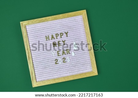 Wish text in English Happy New Year 2023 on felt letter board on green background. Top view. Copy space for text. Selective focus.