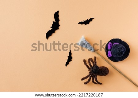 Halloween concept. A black hat, a witch's broom and black bats and spider on an orange background