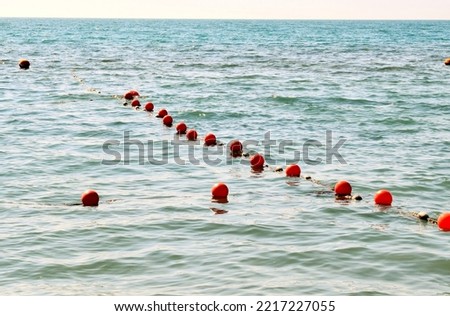 Orange buoys in the sea limiting the safe area for swimming Royalty-Free Stock Photo #2217227055