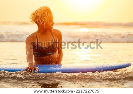 african american surfer woman in water enjoying sunset