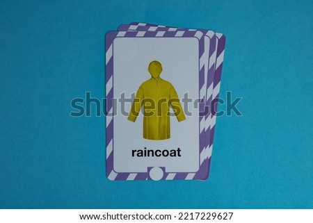 Flashcard with photo of yellow raincoat placed over blue background.