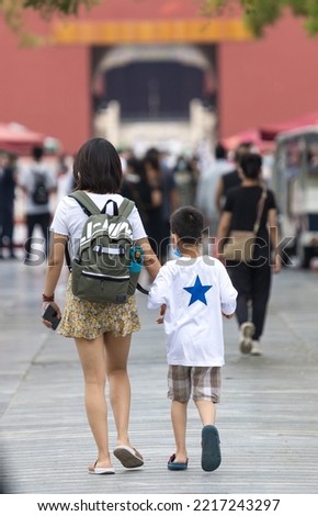 A mother and son walk in the garden of the forbidden city on a summer day in Beijing, China. There is neither face nor a recognizable person or brand name in the photo.