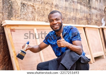 image of cheerful african man with a painting brush, thumbs up sign.