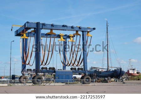Large empty mobile boat travel lift in a harbour under a blue sky. Yacht Service in a yacht marina. Lifts large boats for maintenance, repaint and refitting. Royalty-Free Stock Photo #2217253597
