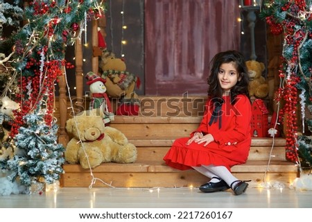 Baby girl in festive attire is in the room decorated for the new year and Christmas. The concept of holidays and gifts.