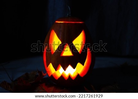 Halloween's holiday attributes. Lantern carved from pumpkin known as Jack-o-lantern glow in the dark on a black background with spider webs, autumn leaves and balloons. Trick or treat.