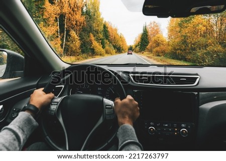 Man driving car on the country road in autumn. Rear view Royalty-Free Stock Photo #2217263797