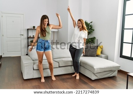Mother and daughter smiling confident dancing at home