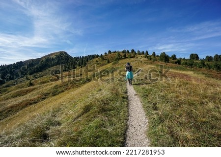 Panoramic view: Young beautiful sporty hiker woman hiking on wonderful path at seceda peak near odles group. Hiking direction piz pic. nature, travel and holiday concept.