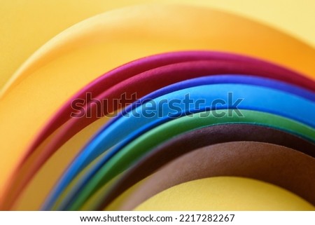 Colorful paper strips on yellow hammer paper, abstract background with vibrant colors, shallow depth of field, blurred lines