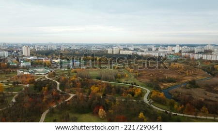 Autumn city park. Trees with colorful leaves. A cycle path winds between the trees. Autumn landscape. Aerial photography.