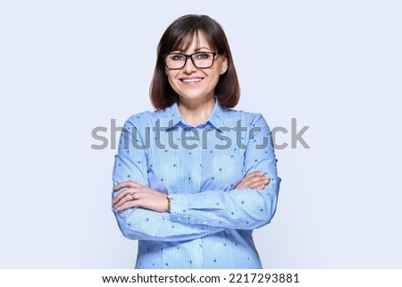 Middle aged smiling business woman over light background Royalty-Free Stock Photo #2217293881