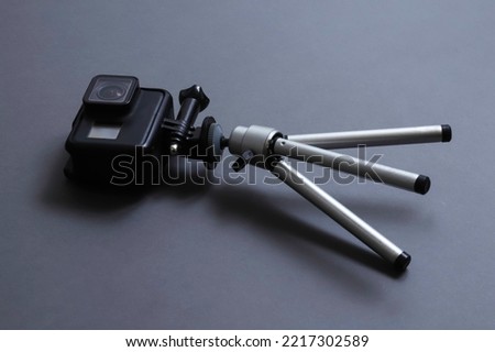 An action camera on a miniature tripod tipped over on a table. Shallow depth of field
