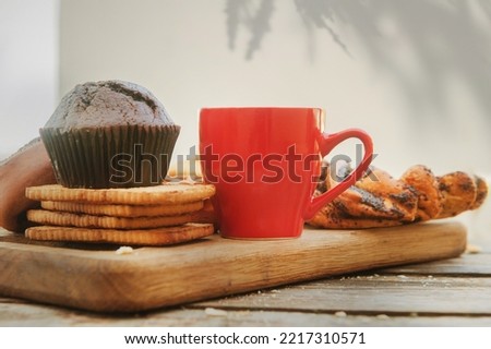 Empty space red coffee cup template with chocolate muffin in outdoor cafe