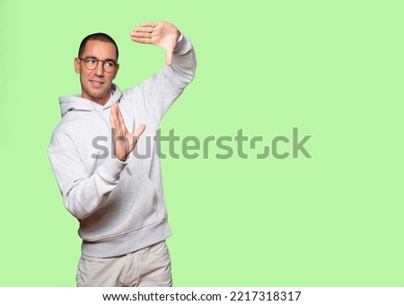 Friendly young man making a gesture of taking a photo with the hands