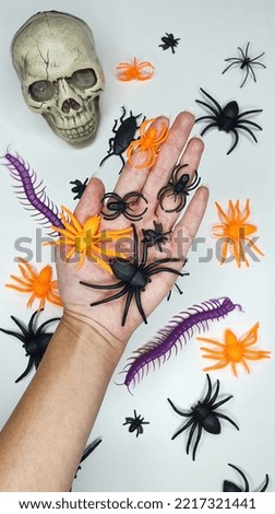 Hand with spiders, centipedes, cockroaches and a skull for halloween