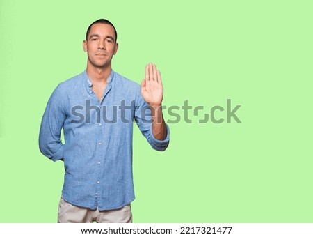 Happy young man making a gesture of stop with his palm