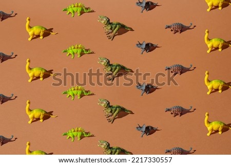 Colorful plastic dinosaur toys on a brown background. Pattern.
