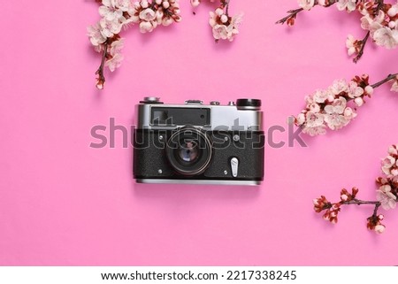 Retro Camera with beautiful pink flowering branches on pink background. Springtime concept. Flat lay, top view