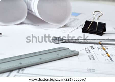 Designer's tools, construction drawings and wrench. Free space on white background. Translation: "construction of the foundation of a residential building, plus some minor explanations"