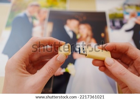 selective focus. printed wedding photos, a wooden box and hands with a flash drive. the concept of preserving the memory of an important event, the services of a professional photographer.