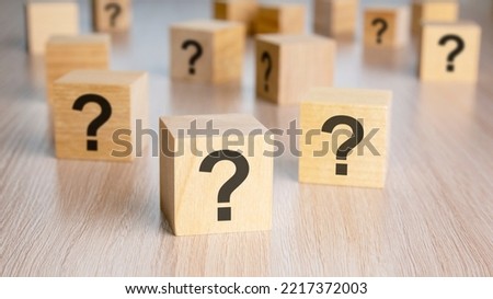 front view on many wood cubes with question marks on wooden background. many trouble and confusion concept.