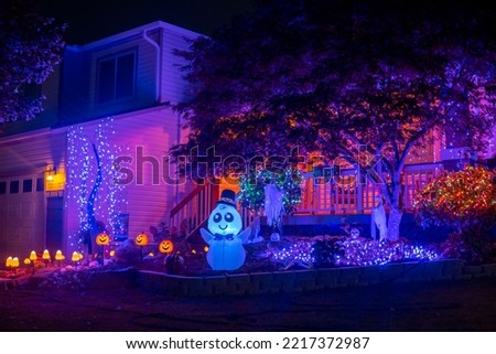 Illuminated night Halloween house outdoor decorations with colorful lights, lanterns, monsters and glow garlands