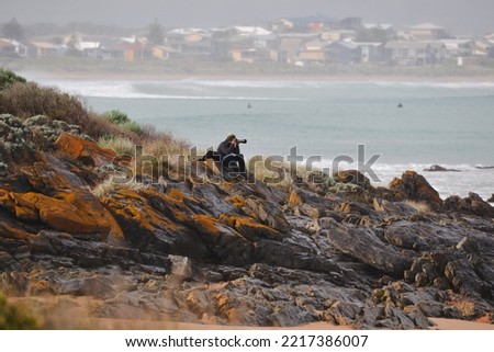 Photographer sitting on rocks at beach