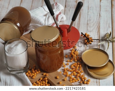 The concept of harvesting jam from healthy sea buckthorn for future use.Glass jars with jam on a wooden background.Autumn. Royalty-Free Stock Photo #2217423181