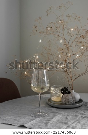 Cozy evening - a glass of white wine, autumn decorations in the living room interior Royalty-Free Stock Photo #2217436863